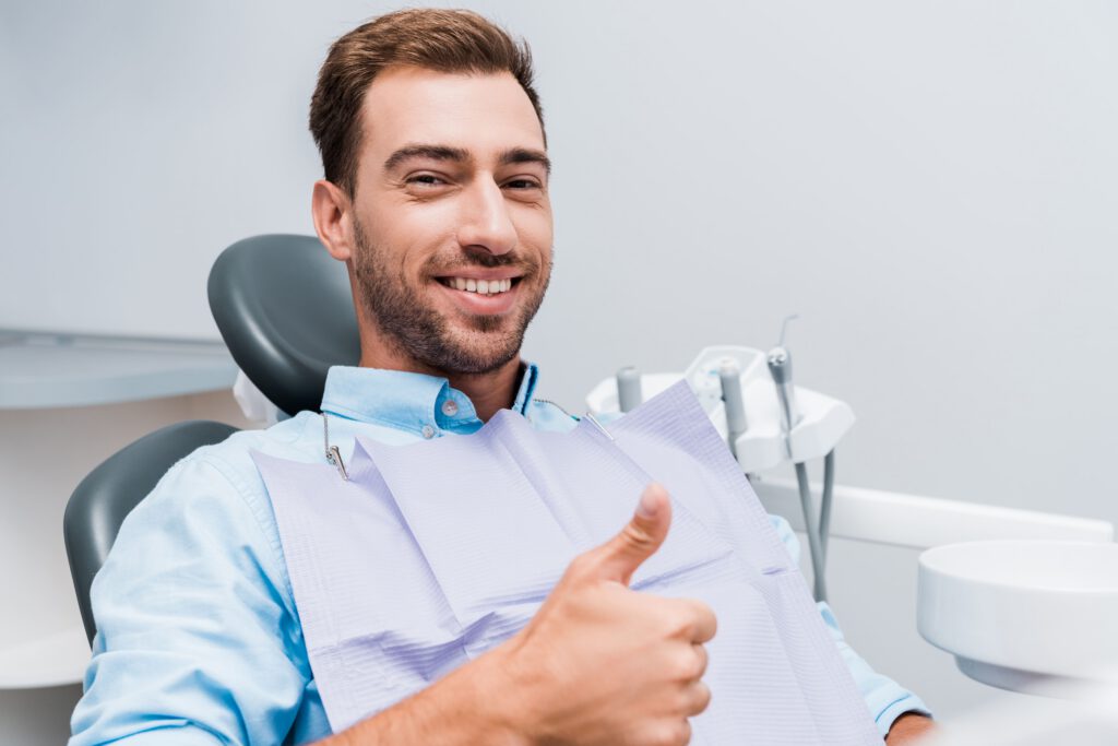 Happy dental patient showing thumbs up after successful treatment